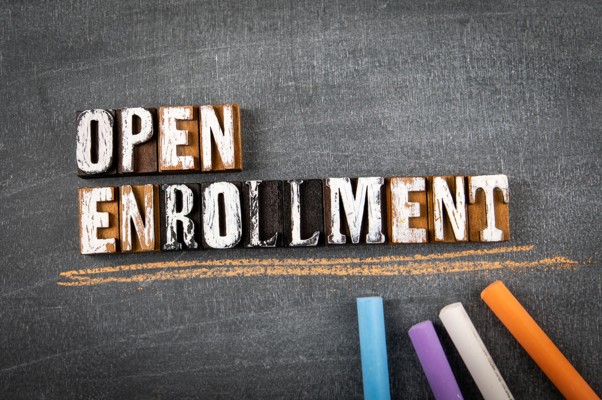 Open Enrollment spelled out in letterpress blocks on a chalkboard
